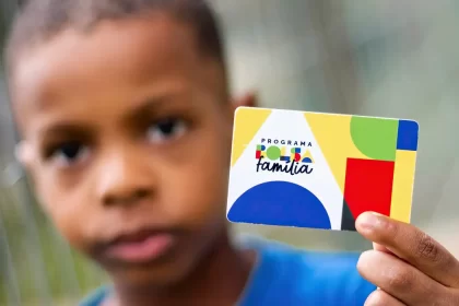 Imagem colorida mostra criança segurando cartão do Bolsa Família