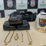 Apreensão de drogas, maconha, em pacotes, além de joias e um boné do BPTran, em cima de uma mesa com o logotipo da Polícia Civil do Amazonas.