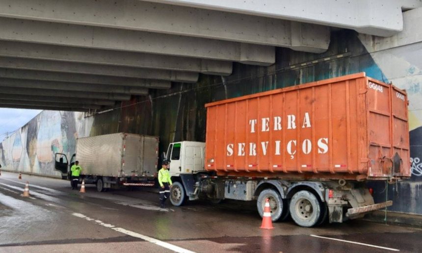 Caminhão com a inscrição 'Terra Serviços' parado embaixo de um viaduto durante fiscalização de carga pesada na avenida Governador José Lindoso.