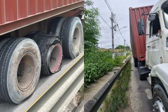 Caminhão com pneus estourados parado na via pública, com um dos pneus completamente desfeito.