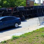 Carreta tombada na estrada com um carro azul parado próximo. O acidente ocorreu na Estrada da Colônia Antônio Aleixo, em frente ao Centro do Alumínio.