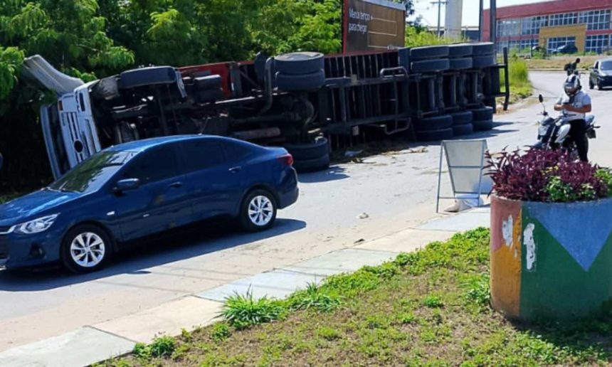 Carreta tombada na estrada com um carro azul parado próximo. O acidente ocorreu na Estrada da Colônia Antônio Aleixo, em frente ao Centro do Alumínio.