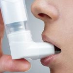 Close-up de uma pessoa usando um inalador para tratar a asma.