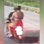 Corpo de uma mulher em uma motocicleta, com um homem atrás dela, ambos mortos. Cena de crime.