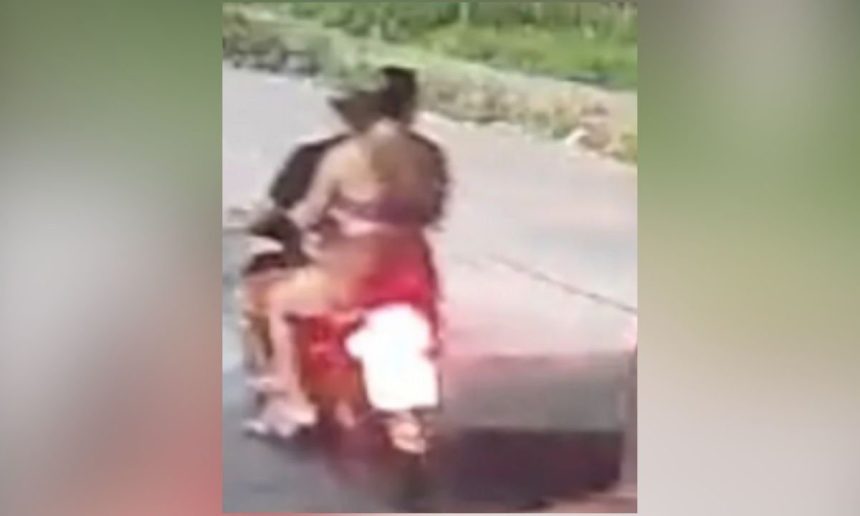 Corpo de uma mulher em uma motocicleta, com um homem atrás dela, ambos mortos. Cena de crime.