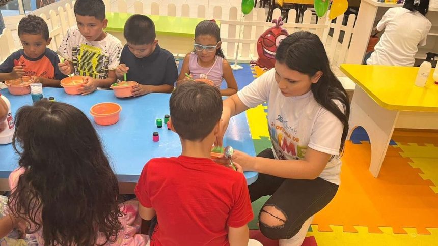Crianças participando de uma atividade artística com um adulto, com o personagem Stitch do desenho animado Lilo & Stitch, em um ambiente de brinquedoteca no Millennium Shopping.