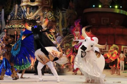 Dançarinos vestidos como bois durante o Festival Folclórico de Parintins, com figurinos elaborados e penas vibrantes.