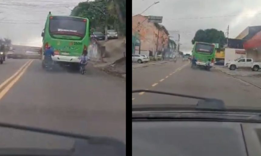 Dois ciclistas andam lado a lado, um deles em frente a um ônibus em movimento, na avenida dos Franceses em Manaus.