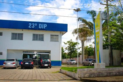 Fachada da delegacia de polícia com a placa 23º DIP em destaque, carros estacionados em frente.