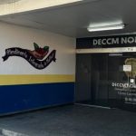 Fachada da Delegacia Especializada em Crimes Contra a Mulher, com a frase "Atendimento Integrado à Mulher" em destaque.