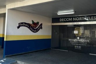 Fachada da Delegacia Especializada em Crimes Contra a Mulher, com a frase "Atendimento Integrado à Mulher" em destaque.