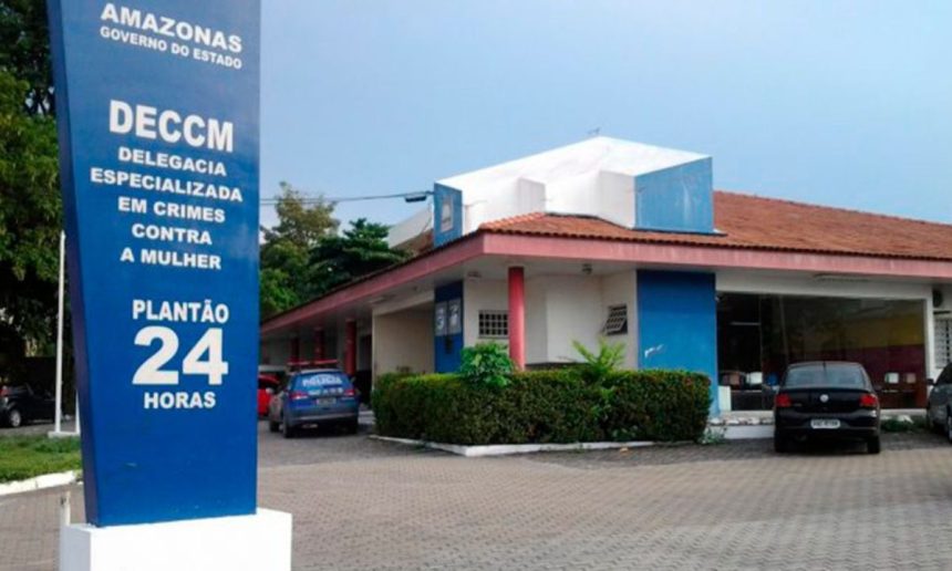 Fachada da Delegacia Especializada em Crimes Contra a Mulher (DECCM) em Manaus, Amazonas, com a placa de plantão 24 horas.