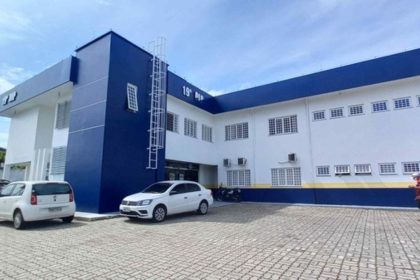 Fachada de um prédio com a inscrição '19ª DP' em destaque, indicando uma delegacia de polícia.