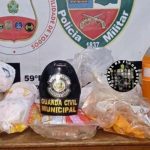 Foto de apreensão de drogas em Japurá, Amazonas. A imagem mostra diversos pacotes de drogas, além de bebidas e um chapéu de guarda civil municipal.