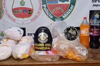 Foto de apreensão de drogas em Japurá, Amazonas. A imagem mostra diversos pacotes de drogas, além de bebidas e um chapéu de guarda civil municipal.