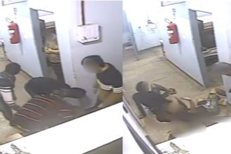 Imagem de uma briga em uma delegacia, com um detento caído no chão e outros dois presos em pé, um deles com uma camisa verde e o outro com uma camisa preta.