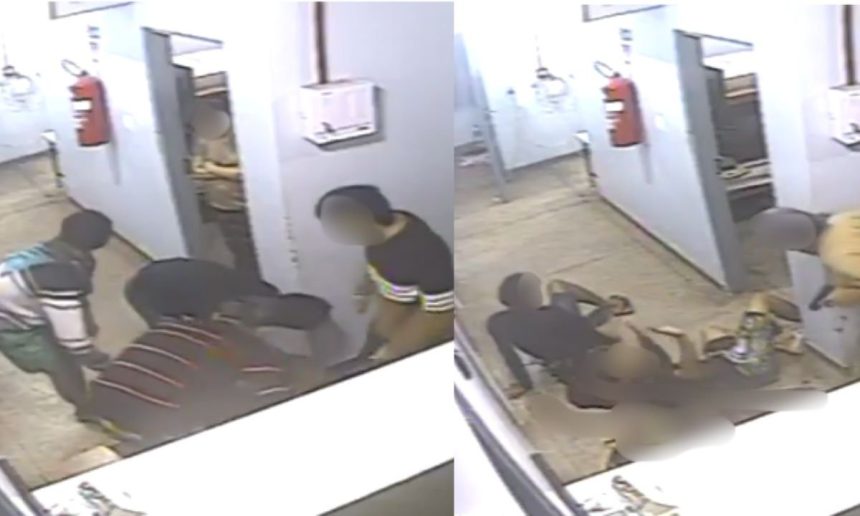 Imagem de uma briga em uma delegacia, com um detento caído no chão e outros dois presos em pé, um deles com uma camisa verde e o outro com uma camisa preta.