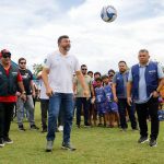 O governador Wilson Lima entrega um estádio modernizado, com crianças jogando bola e autoridades presentes.