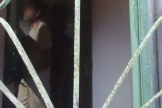 Pessoa em ambiente interno, possivelmente em situação de violência doméstica