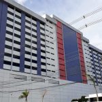 Prédio da Faculdade Metropolitana de Manaus (Fametro), com fachada moderna em tons de branco, azul e vermelho, e muitas janelas.