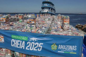 Um barco cheio de pacotes de alimentos, sinalizado com 'Operação Cheia 2025' e 'Defesa Civil Amazonas', para ajudar vítimas de enchentes no Amazonas.