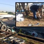 Um caminhão tombado em um acidente com um homem ao fundo no local do acidente