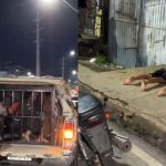 Um casal preso em uma viatura da polícia, ambos com as mãos algemadas e sendo escoltados por policiais militares.