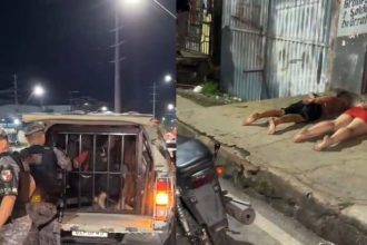 Um casal preso em uma viatura da polícia, ambos com as mãos algemadas e sendo escoltados por policiais militares.