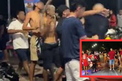 Um grupo de pessoas em uma rua à noite, algumas delas usando camisetas vermelhas. No fundo, um policial de moto. A imagem pode ser relacionada a um incidente de violência.