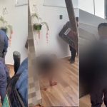 Um homem deitado no chão com policiais ao redor, em uma casa. Há sangue no chão, sugerindo uma situação violenta.