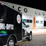 Um veículo preto e branco da polícia, possivelmente uma van, estacionado em frente a um prédio com a placa "Colegial" em destaque.