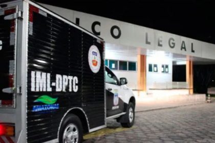 Um veículo preto e branco da polícia, possivelmente uma van, estacionado em frente a um prédio com a placa "Colegial" em destaque.