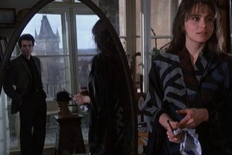 Uma cena do filme 'A Insustentável Leveza do Ser', com um homem refletido em um espelho e uma mulher em primeiro plano.