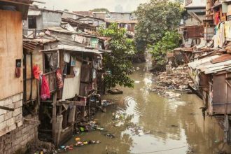 Vista de um igarapé poluído em Manaus, com casas improvisadas nas margens.