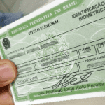 Imagem colorida mostra título de eleitor na mão de uma pessoa