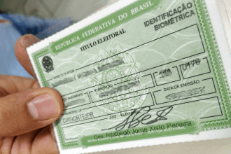 Imagem colorida mostra título de eleitor na mão de uma pessoa