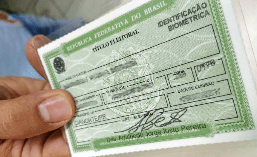Imagem colorida mostra título de eleitor na mão de uma pessoa