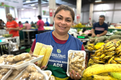 Imagem colorida mostra Feirante oferecendo seus produtos na Feira da ADS