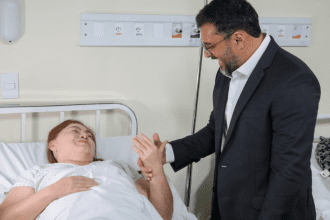 Imagem colorida mostra o governador Wilson Lima conversando com uma paciente no hospital Adriano Jorge