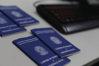 Imagem colorida mostra carteiras de trabalho sobre uma mesa