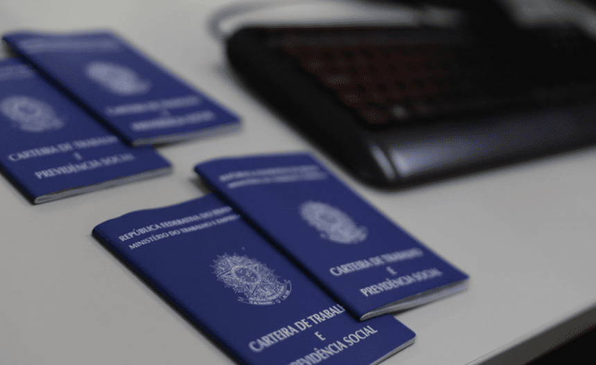 Imagem colorida mostra carteiras de trabalho sobre uma mesa