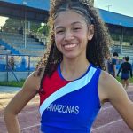Samara Macena, atleta amazonense, celebra vitória no atletismo, com braços erguidos e sorriso radiante.