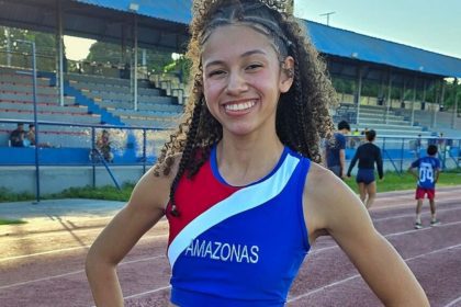 Samara Macena, atleta amazonense, celebra vitória no atletismo, com braços erguidos e sorriso radiante.