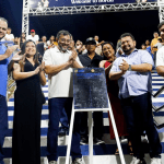 Imagem colorida mostra Wilson Lima com placa de inauguração de iluminação em Borba