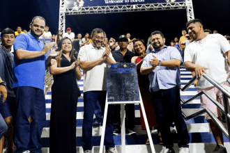 Imagem colorida mostra Wilson Lima com placa de inauguração de iluminação em Borba