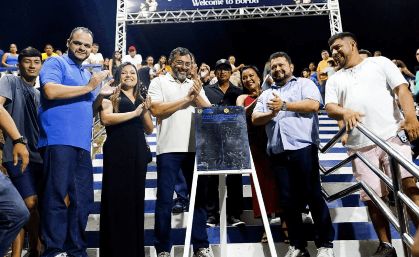 Imagem colorida mostra Wilson Lima com placa de inauguração de iluminação em Borba