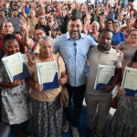 Imagem colorida mostra Wilson Lima entregando títulos definitivos