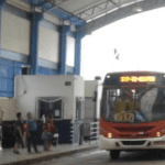 Imagem colorida mostra ônibus e passageiros esperando para pagamento em dinheiro
