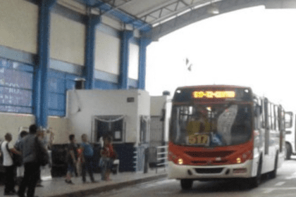 Imagem colorida mostra ônibus e passageiros esperando para pagamento em dinheiro