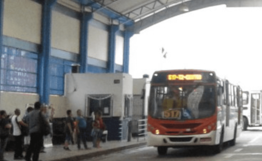 Imagem colorida mostra ônibus e passageiros esperando para pagamento em dinheiro
